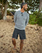 Man wearing black boardshorts and a gray sweater on the beach