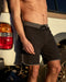 Black scallop hem style trunks with a signature logo on the bottom right and a drawstring waistband.