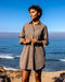 Woman standing on a rocky beach with ocean and clear blue sky in the background