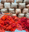 Stack of brown burlap bags with a pile of red fabric on a blue surface.