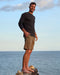 Man standing on a rock by the ocean with a clear sky