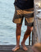 Person wearing striped shorts standing on a wooden dock by the water.