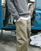 Person wearing a gray sweatshirt and green pants standing next to an open vehicle.