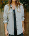 Person wearing a light gray jacket with a wooden background