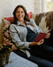 Woman reading a book on a couch with a cat beside her